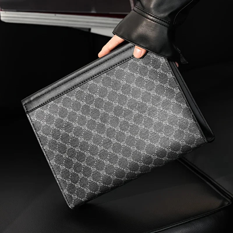Person holding a black and gray patterned clutch bag on a dark background