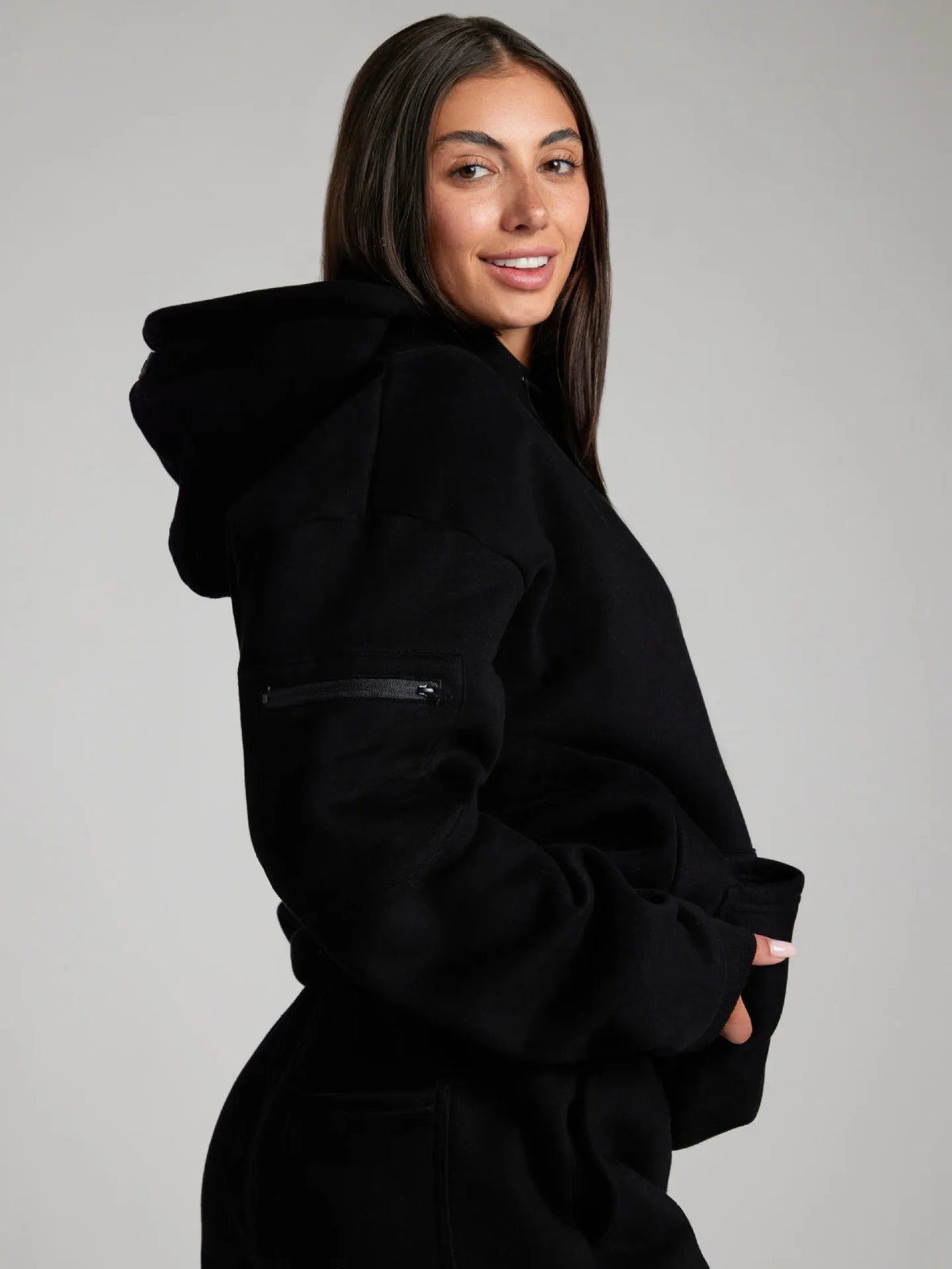 Woman wearing a black hoodie against a gray background