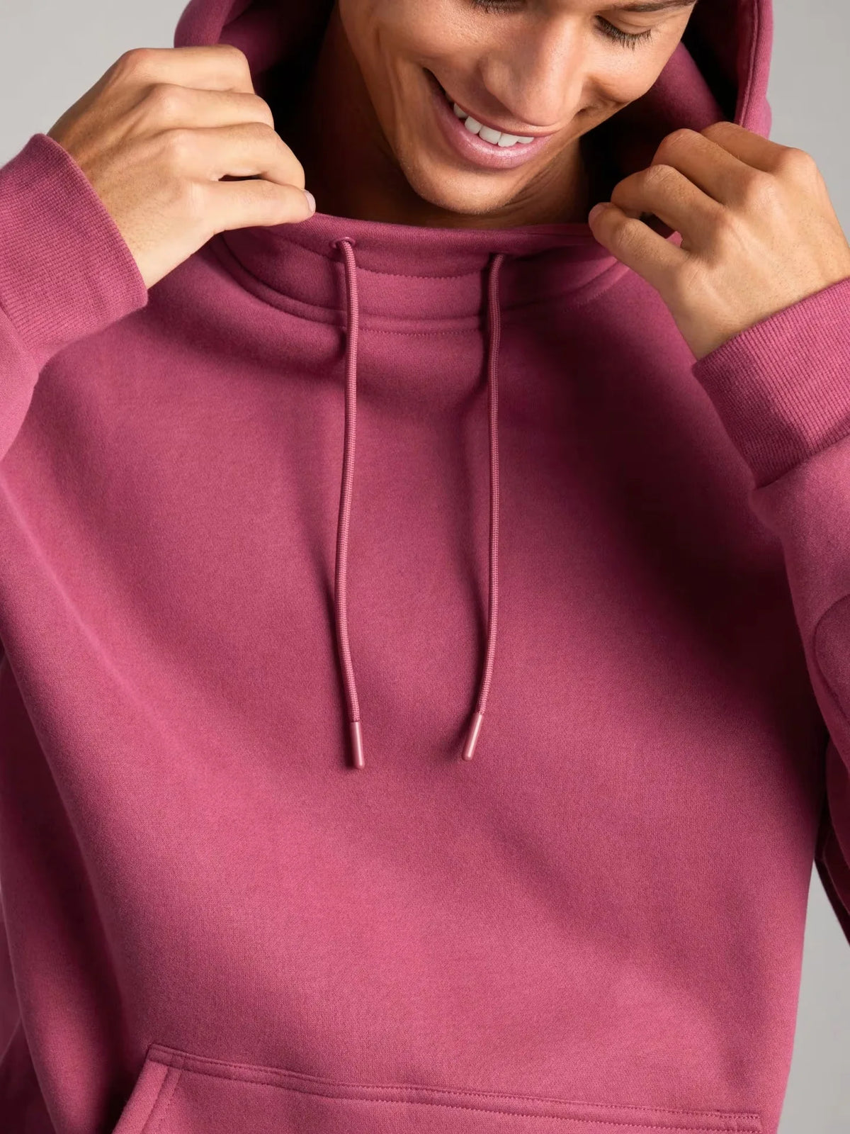 Person wearing a maroon hoodie with a neutral background
