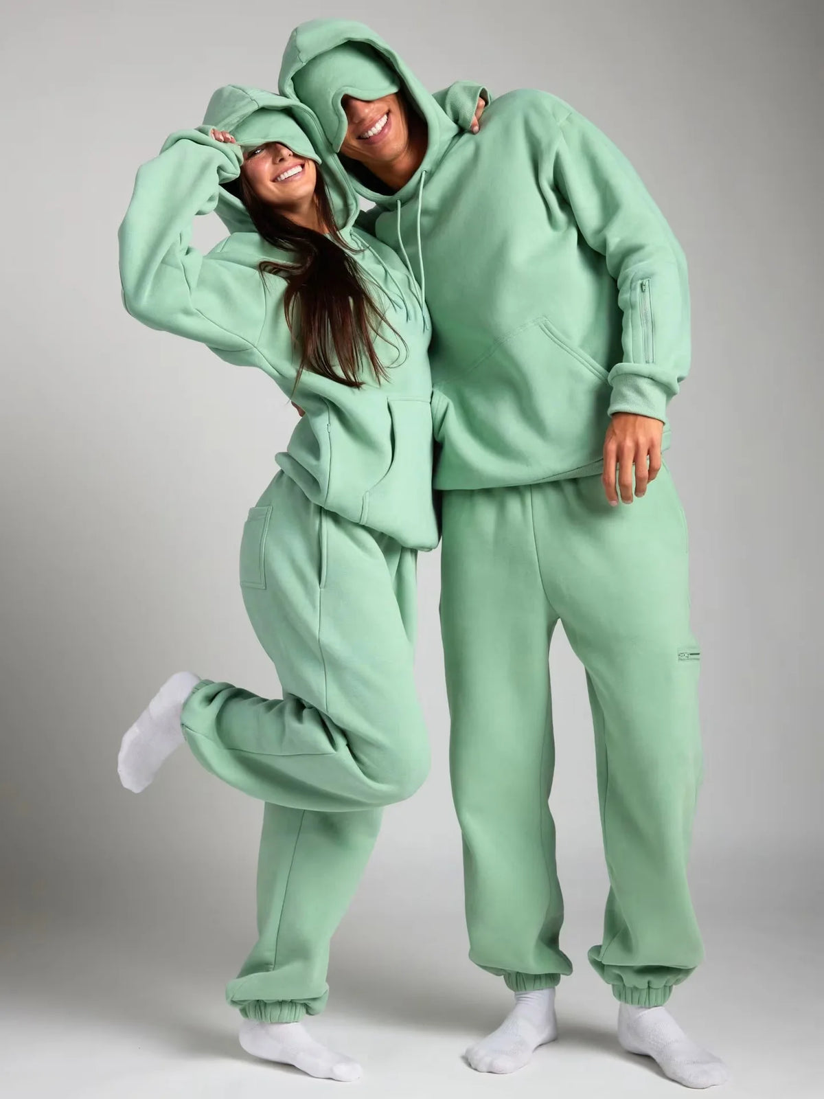 Two people wearing matching green outfits on a plain background