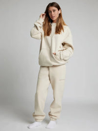 Woman wearing a beige hoodie and pants set on a plain background