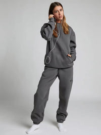 Person wearing a gray tracksuit on a plain background