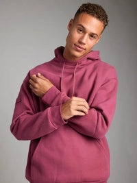 Person wearing a maroon hoodie against a gray background