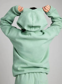 Light green hoodie with a hood held up against a gray background
