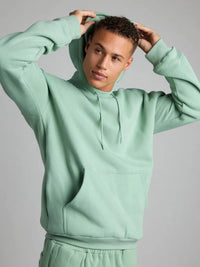 Person wearing a light green hoodie against a gray background