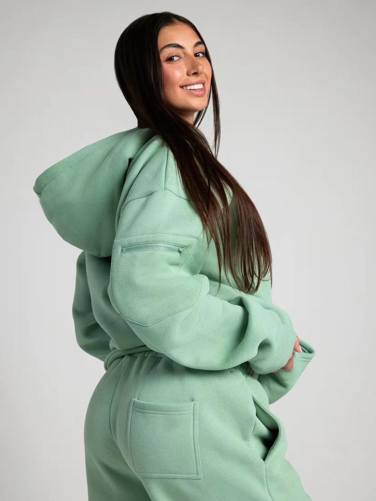 Person wearing a mint green hoodie and pants on a plain background