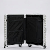 Interior view of Aeria Prestige The Monarch aluminum travel case in Alabaster White Damier finish, featuring dual packing compartments, zippered mesh divider pockets, and compression straps for organized travel.