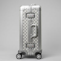 Side profile view of Aeria Prestige The Monarch aluminum travel case in Alabaster White Damier finish, highlighting the dual integrated TSA-approved combination locks, sturdy side handle, and reinforced frame.