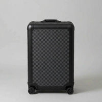 Front view of Aeria Prestige The Monarch aluminum travel case in Matte Obsidian Damier checkered finish, showcasing the sleek black frame, protective corner caps, and smooth spinner wheels.