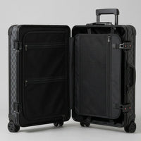 Interior view of Aeria Prestige The Monarch aluminum travel case in Matte Obsidian Damier finish, featuring dual packing compartments, zippered mesh divider pockets, and compression straps for organized travel.
