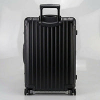 Rear view of The Masterpiece Legacy aluminum luggage by AERIA PRESTIGE in Obsidian Black, featuring a fully extended telescopic handle, zipperless aerospace-grade alloy hardshell, and silent spinner wheels.