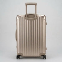 Rear view of The Masterpiece Legacy aluminum luggage by AERIA PRESTIGE in Rose Champagne, showing the fully extended telescopic trolley handle, aerospace-grade alloy hardshell, and silent multi-directional spinner wheels.