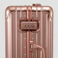 Close-up of the integrated dual TSA-approved combination locks on The Masterpiece Legacy aluminum luggage by AERIA PRESTIGE in Rose Gold, showcasing precision engineering and bank-grade security.