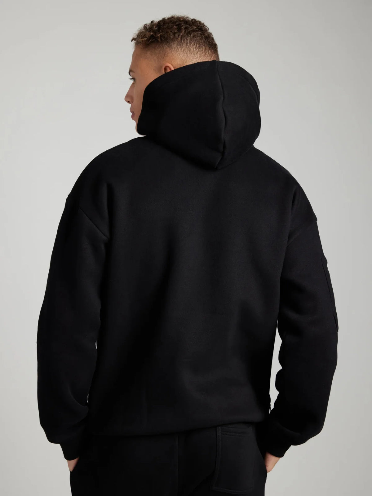 Person wearing a black hoodie from behind on a plain background
