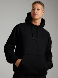 Person wearing a black hoodie against a gray background