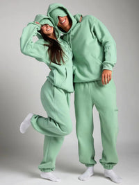 Two people wearing matching green outfits on a plain background