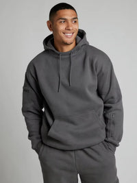 Man wearing a gray hoodie and pants on a plain background