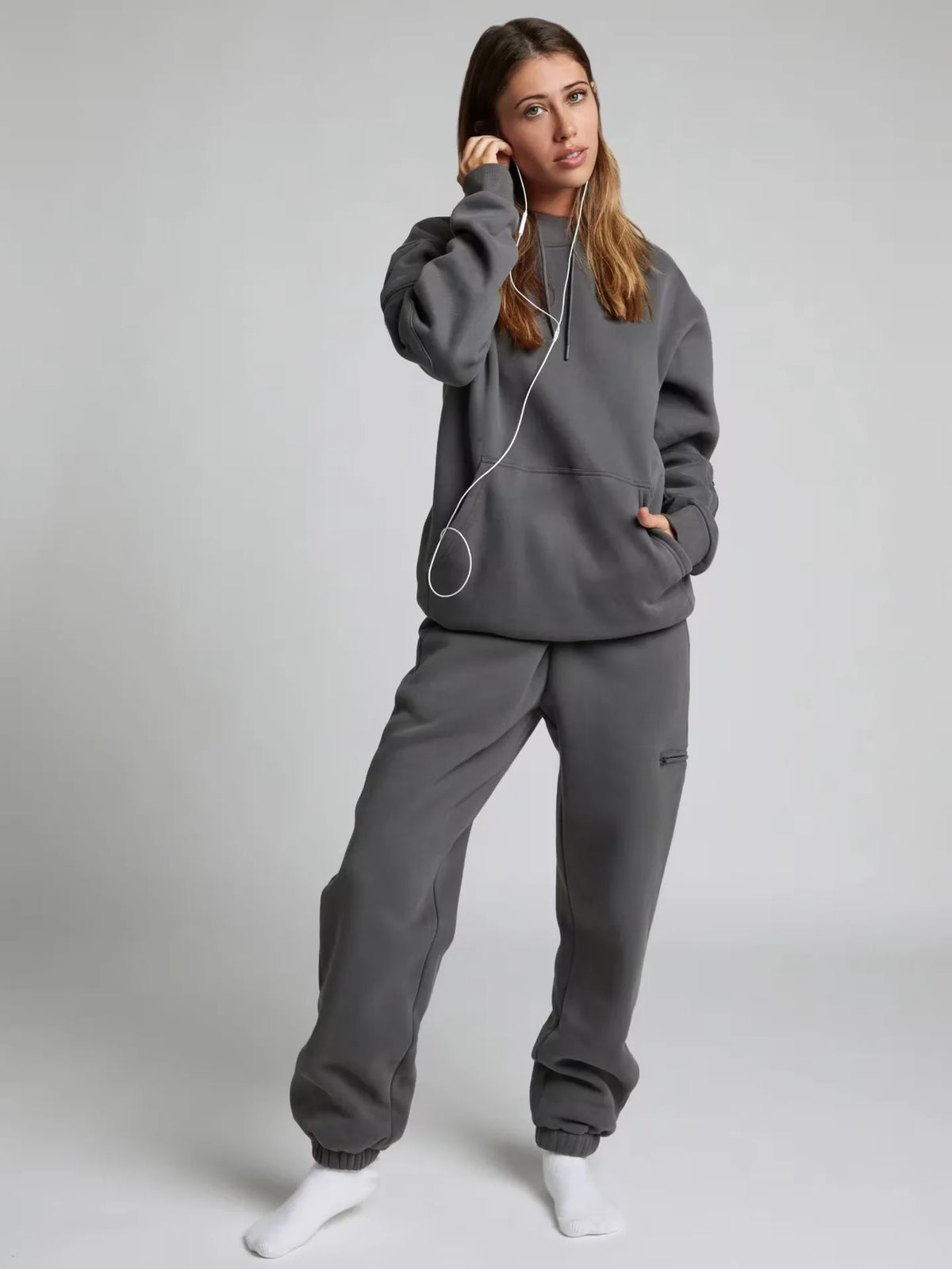 Person wearing a gray tracksuit on a plain background