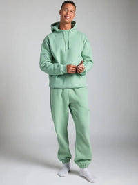 Person wearing a light green tracksuit against a plain background