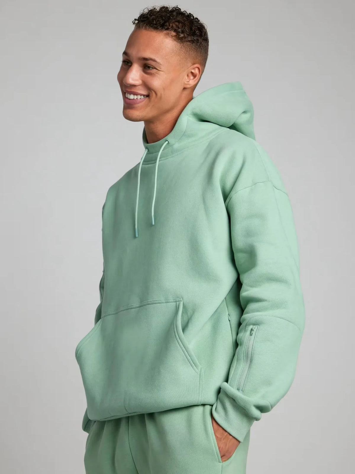 Person wearing a light green hoodie on a plain background