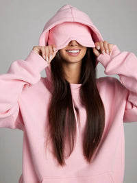 Person wearing a pink hoodie with a plain background