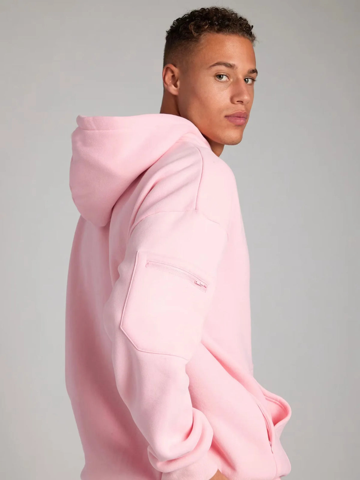 Person wearing a pink hoodie against a gray background