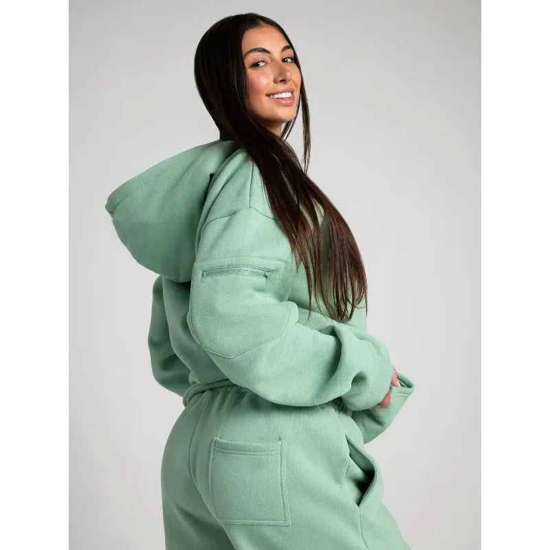 Person wearing a light green hoodie and pants on a plain background