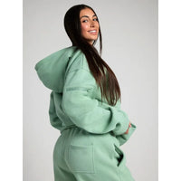 Person wearing a light green hoodie and pants on a plain background