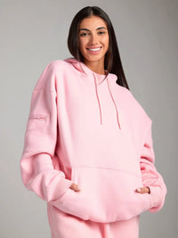 Person wearing a pink hoodie against a gray background