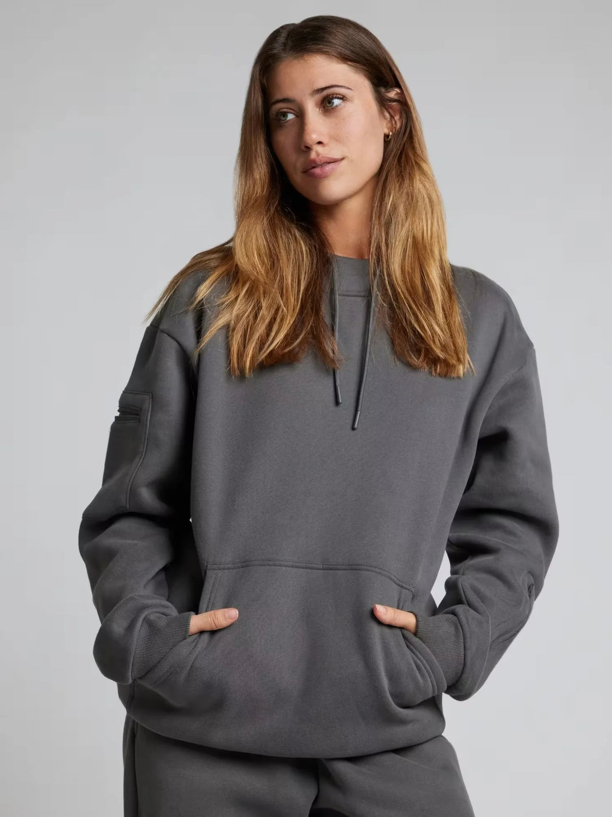 Woman wearing a gray hoodie against a plain background