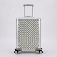 Front view of Aeria Prestige The Monarch aluminum travel case in Alabaster White Damier checkered pattern, showcasing its metallic frame, corner protectors, and smooth spinner wheels.