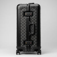 Side profile view of Aeria Prestige The Monarch aluminum travel case in Matte Obsidian Damier finish, highlighting the dual integrated TSA-approved combination locks, sturdy side handle, and reinforced frame.