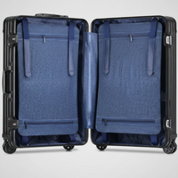A studio view of The Masterpiece — The Legacy aluminum-magnesium alloy travel case in Deep Azure, shown open against a clean white background. The interior features the modular compression system with high-density straps, revealing the organized layout designed for executive travel. The exterior metallic shell showcases its signature grooved, zipperless design. No external branding is visible on the suitcase.