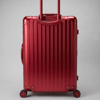 Rear view of The Masterpiece Legacy aluminum luggage by AERIA PRESTIGE in Imperial Red, featuring a fully extended telescopic handle, zipperless aerospace-grade alloy hardshell, and silent multi-directional spinner wheels.